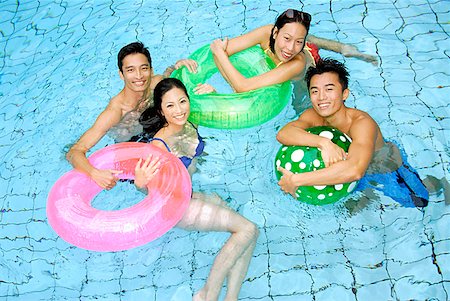 Couples in swimming pool with floats looking at camera Stock Photo - Premium Royalty-Free, Code: 656-01769619