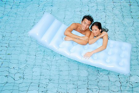 Couple in swimming pool leaning on pool raft Stock Photo - Premium Royalty-Free, Code: 656-01769621
