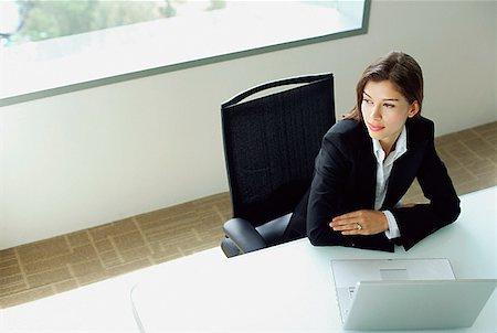 Businesswoman sitting at table, arms crossed, laptop in front of her Stock Photo - Premium Royalty-Free, Code: 656-01769970