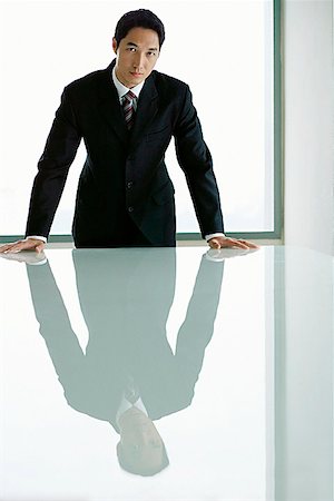 Businessman standing with hands on table, looking at camera Stock Photo - Premium Royalty-Free, Code: 656-01769997