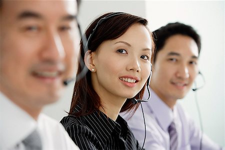 simsearch:628-02954142,k - Executives in a row, wearing headsets, smiling at camera Fotografie stock - Premium Royalty-Free, Codice: 656-01770026