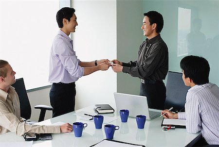 Executives in meeting room, exchanging business cards Stock Photo - Premium Royalty-Free, Code: 656-01770055