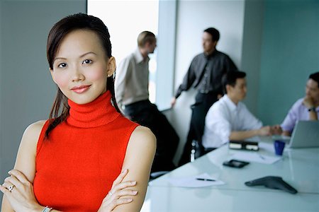 simsearch:614-06116477,k - Female executive, arms crossed, looking at camera, people in the background Stock Photo - Premium Royalty-Free, Code: 656-01770067