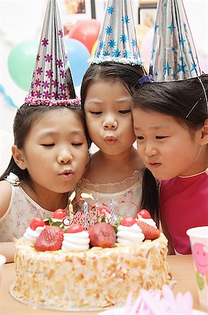 east asian ethnicity girl cake - Three girls celebrating a birthday, blowing birthday candles Stock Photo - Premium Royalty-Free, Code: 656-01770510