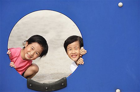 Two girls in playground, looking through hole Stock Photo - Premium Royalty-Free, Code: 656-01770590
