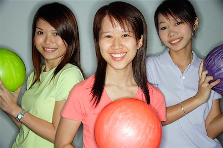 simsearch:656-01770741,k - Three young women holding bowling balls, smiling at camera Foto de stock - Royalty Free Premium, Número: 656-01770658