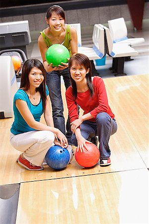 simsearch:656-01770739,k - Three women in bowling alley, with bowling balls, smiling at camera Fotografie stock - Premium Royalty-Free, Codice: 656-01770669