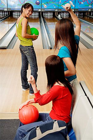 simsearch:656-01770741,k - Women in bowling alley, one woman about to bowl, friends cheering her on Foto de stock - Royalty Free Premium, Número: 656-01770672