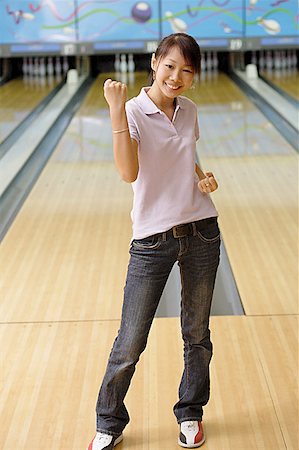 Woman standing at bowling alley, smiling, making a fist Stock Photo - Premium Royalty-Free, Code: 656-01770708