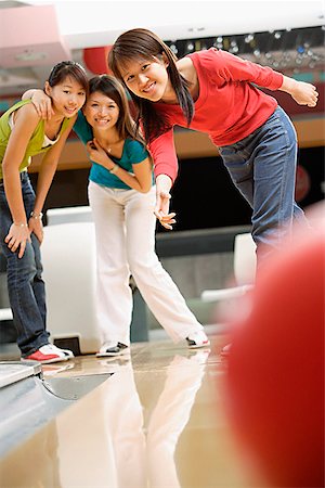 simsearch:656-01770741,k - Three women at a bowling alley, bowling ball in the foreground Foto de stock - Royalty Free Premium, Número: 656-01770735