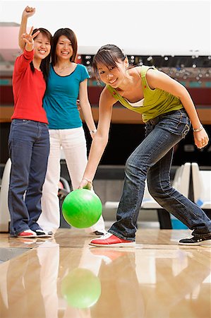 simsearch:656-01770739,k - Woman bowling, friends watching her in the background Fotografie stock - Premium Royalty-Free, Codice: 656-01770730
