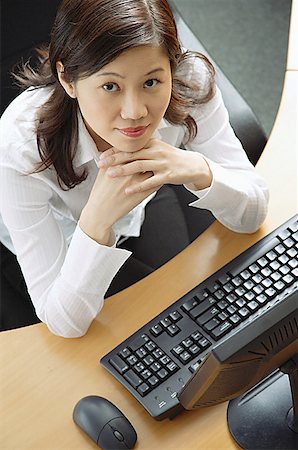 desk directly above - Businesswoman sitting in office cubicle, hands on chin, looking up at camera Stock Photo - Premium Royalty-Free, Code: 656-01770841
