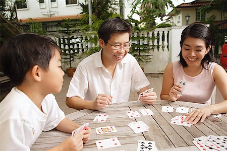 Group of Asian friends playing card games for fun in a hostel