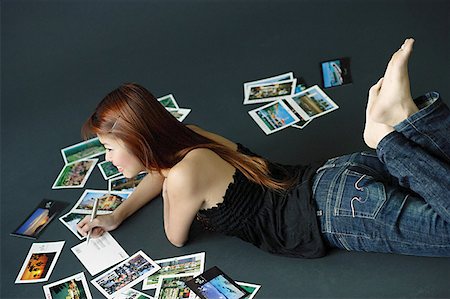 postcard - Woman lying on floor, writing on backs of postcards Stock Photo - Premium Royalty-Free, Code: 656-01771047