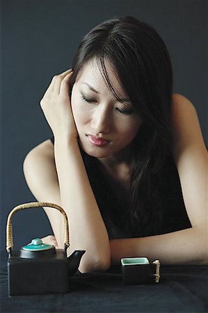 Woman with eyes closed, teacup and teapot next to her Stock Photo - Premium Royalty-Free, Code: 656-01771072