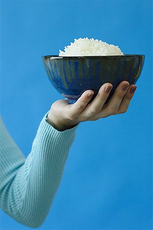 Woman holding bowl of rice in one hand Stock Photo - Premium Royalty-Free, Code: 656-01771154