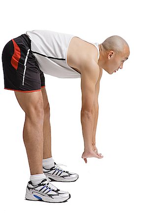 shaved head profile asian - Young man bending over doing stretching exercise Stock Photo - Premium Royalty-Free, Code: 656-01771371