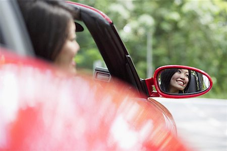 Woman in red sports car, reflected in side view mirror Stock Photo - Premium Royalty-Free, Code: 656-01771462