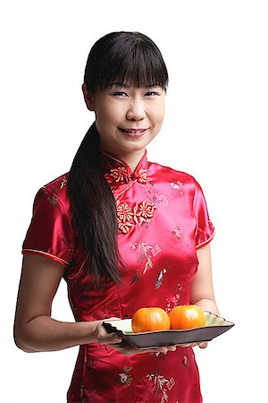 Woman in Cheongsam, holding plate with two oranges Stock Photo - Premium Royalty-Free, Code: 656-01771516