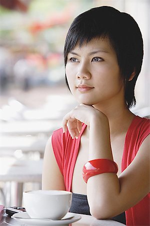 Woman with hand on chin, cup and saucer next to her Stock Photo - Premium Royalty-Free, Code: 656-01771597