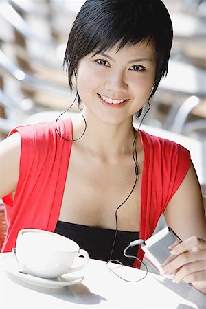 Woman at cafe, listening to MP3 player Stock Photo - Premium Royalty-Free, Code: 656-01771591