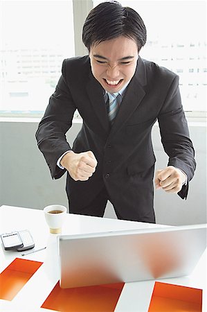 Businessman standing, looking at laptop, making a face Stock Photo - Premium Royalty-Free, Code: 656-01771694