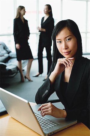 simsearch:693-03303488,k - Businesswoman using laptop, looking at camera, hand on chin Foto de stock - Sin royalties Premium, Código: 656-01771822