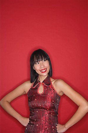 Woman dressed in cheongsam, hands on hips, smiling Stock Photo - Premium Royalty-Free, Code: 656-01771839