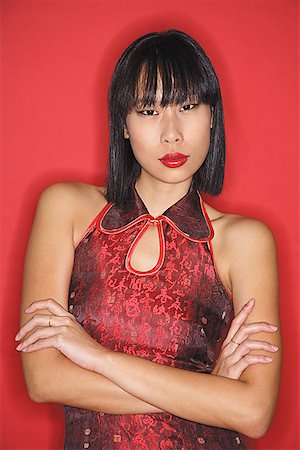 simsearch:656-01770941,k - Woman against red background, dressed in cheongsam, arms crossed Foto de stock - Sin royalties Premium, Código: 656-01771841