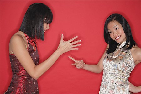 pedra papel tesoura - Two women in cheongsams, playing hand game Foto de stock - Royalty Free Premium, Número: 656-01771869