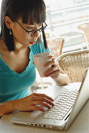 simsearch:656-01766118,k - Young woman in cafe, holding cup and using laptop Foto de stock - Royalty Free Premium, Número: 656-01772111