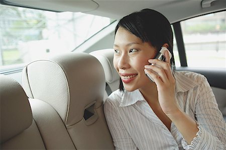 Businesswoman in backseat of car using mobile phone, smiling Foto de stock - Sin royalties Premium, Código: 656-01772189