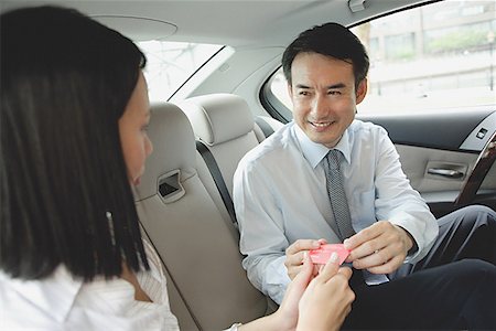 Businessman and businesswoman in backseat of car, exchanging business cards Stock Photo - Premium Royalty-Free, Code: 656-01772190