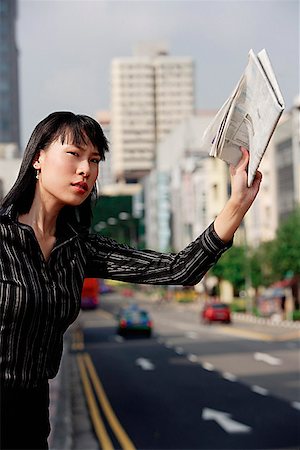 picture of someone hailing a taxi - Businesswoman hailing a taxi with newspaper in hand Stock Photo - Premium Royalty-Free, Code: 656-01772251