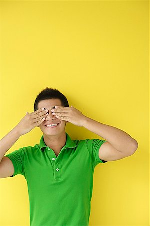 Man standing against yellow wall, covering eyes Fotografie stock - Premium Royalty-Free, Codice: 656-01772286