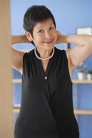 Mature woman putting on pearl necklace Stock Photo - Premium Royalty-Free, Code: 656-01772327