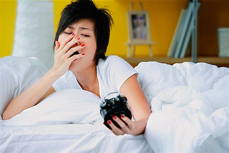 simsearch:656-01773560,k - Woman in bed, looking at alarm clock, yawning Stock Photo - Premium Royalty-Free, Code: 656-01772496
