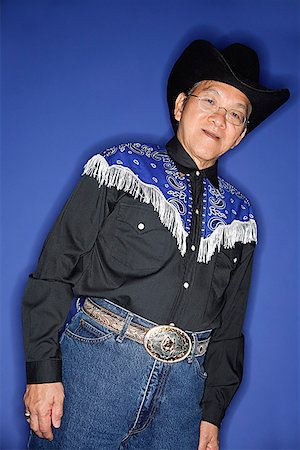 simsearch:656-01772656,k - Senior man dressed in cowboy attire, standing against blue background Stock Photo - Premium Royalty-Free, Code: 656-01772594