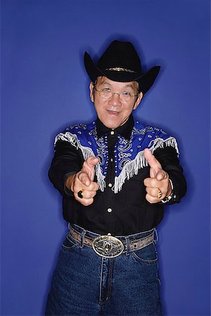 Senior man dressed in cowboy attire, pointing fingers at camera Stock Photo - Premium Royalty-Free, Code: 656-01772593