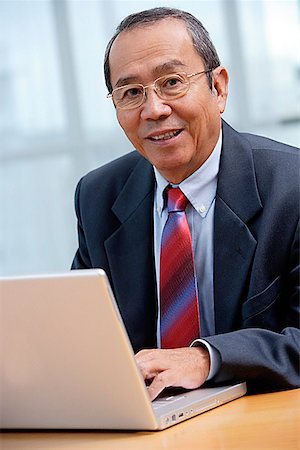 simsearch:656-01772656,k - Businessman with laptop, smiling at camera Stock Photo - Premium Royalty-Free, Code: 656-01772653