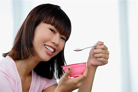 simsearch:656-01771940,k - Young woman eating from pink bowl Fotografie stock - Premium Royalty-Free, Codice: 656-01772679