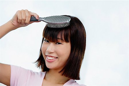 straight hair brushing - Young woman brushing her hair, smiling at camera Foto de stock - Sin royalties Premium, Código: 656-01772681