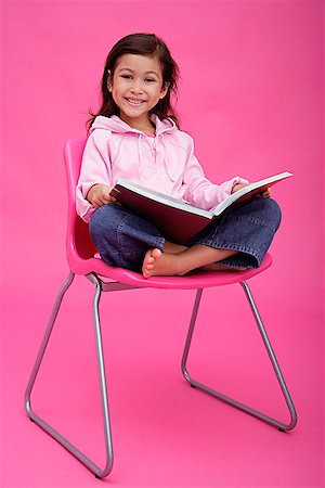 Girl on chair, reading a book, smiling at camera Stock Photo - Premium Royalty-Free, Code: 656-01772776