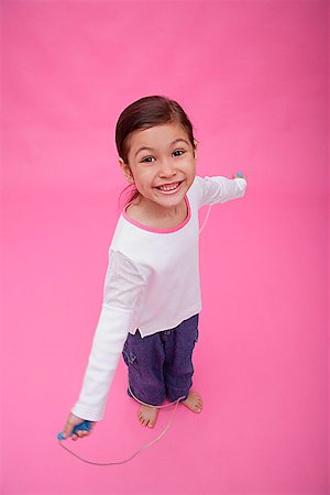 Girl with skipping rope, smiling up at camera Stock Photo - Premium Royalty-Free, Code: 656-01772799