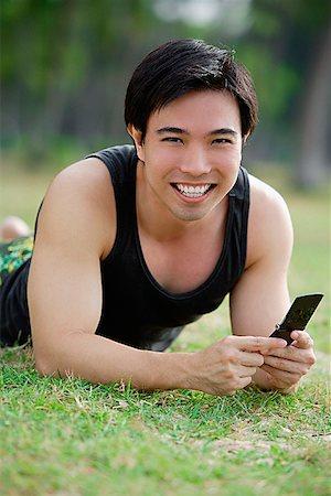 simsearch:656-01766118,k - Man lying on grass, holding mobile phone, smiling at camera Foto de stock - Royalty Free Premium, Número: 656-01772818