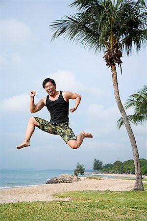 single coconut tree picture - Man jumping in air, looking at camera Stock Photo - Premium Royalty-Free, Code: 656-01772824