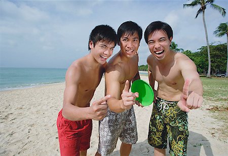 simsearch:656-01772853,k - Men on beach, standing side by side, making hand sign Fotografie stock - Premium Royalty-Free, Codice: 656-01772843