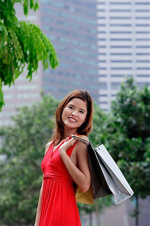 simsearch:656-01773308,k - Femme en robe rouge transportant des sacs à provisions, emplacement de la ville Photographie de stock - Premium Libres de Droits, Code: 656-01772994