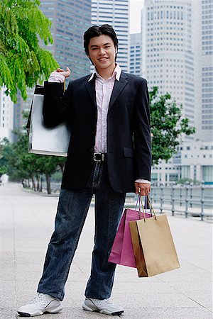 Man standing with shopping bags, smiling at camera Stock Photo - Premium Royalty-Free, Code: 656-01773001