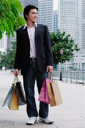 Man standing with shopping bags, looking away Stock Photo - Premium Royalty-Free, Code: 656-01773002